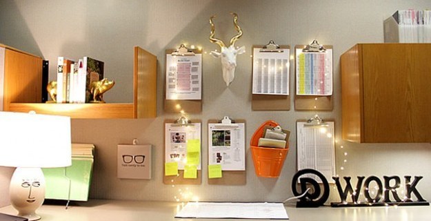an office wall with shelves and assorted documents, decorated in string lights